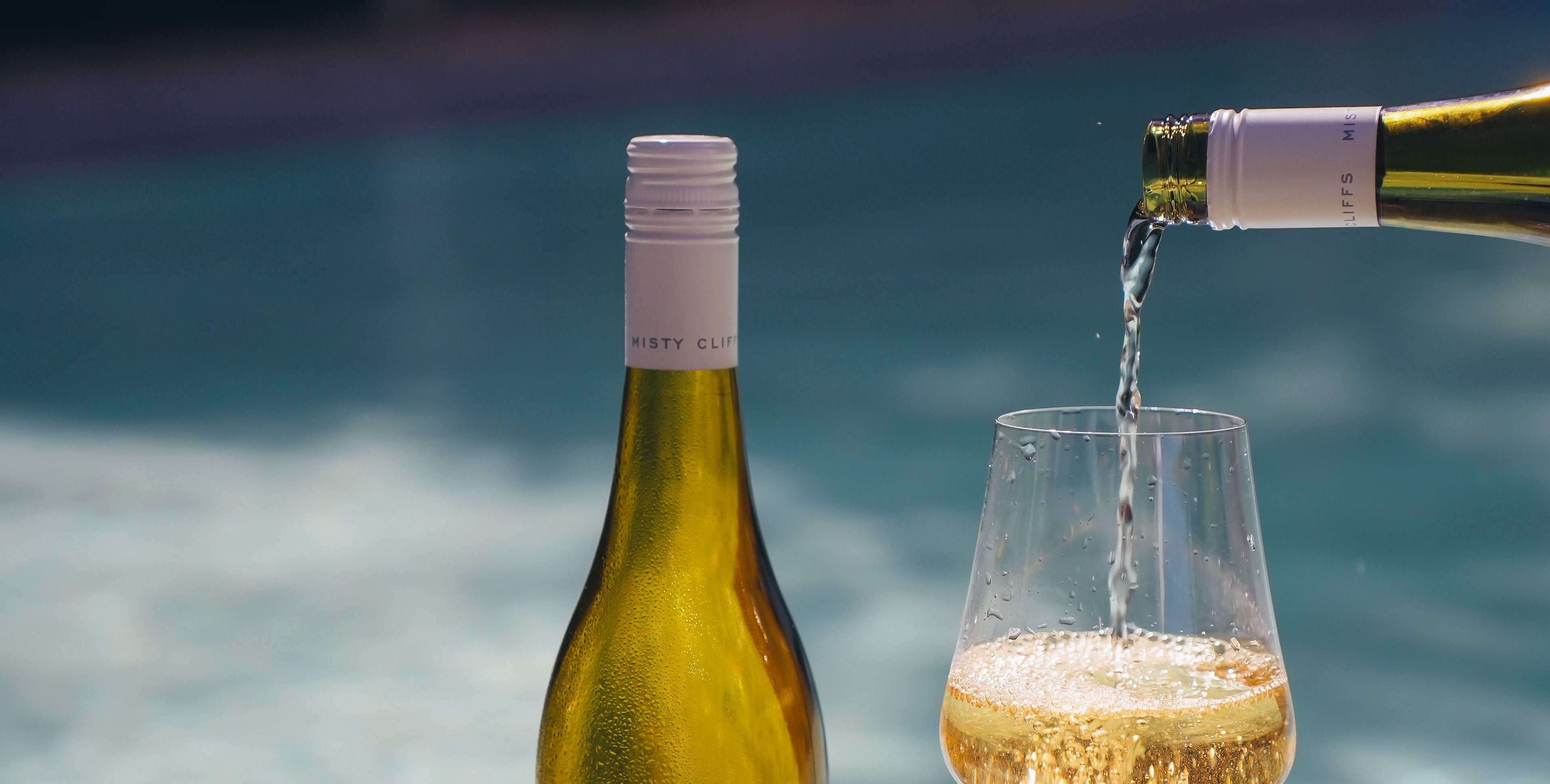 Wine being poured from a bottle into a glass with a blurred pool background